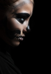 Closeup profile of a girl with make-up skeleton. Halloween portrait. Isolation on a black background