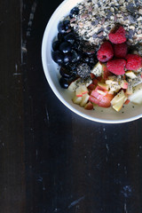 mixed fruit and cereal in a white bowl on brown wooden table