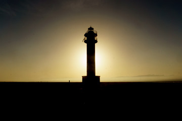 backlit Silhouette of lighthouse during sunset