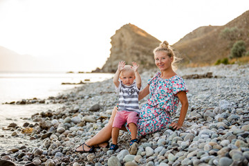 Evening, sea beach. The son sits on his mother's lap and eats fruit and berries