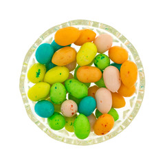 Top view of a small glass bowl filled with colorful Easter eggs candy bubble gum isolated on a white background.