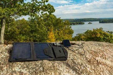 Solar panel charging a smartphone at a remote work location.