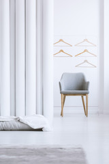 Wooden hangers above gray armchair