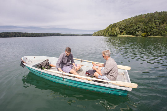 Two caucasian men in a rowboat on the way to do fly fishing on a river.