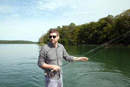 A man is fly fishing from a boat on a lake.