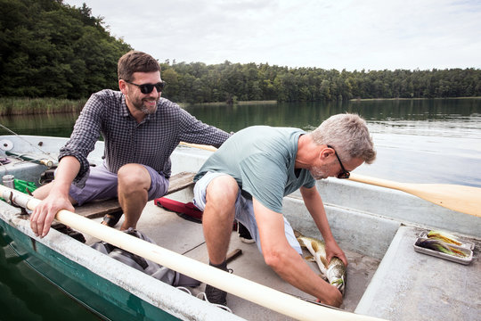 Two fly fishers have catched a pike from a boat on a lake.