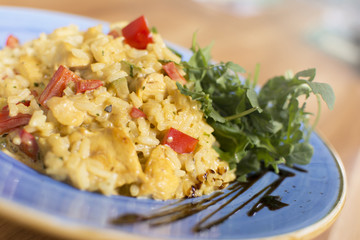 A plate of rice with vegetables. Appetizing healthy rice with vegetables in white plate on a wooden background.