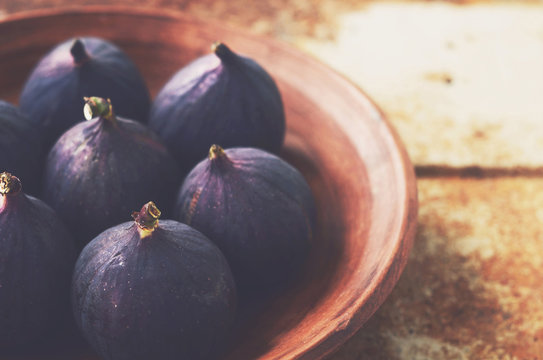Ripe figs in clay bowl on grunge metal background