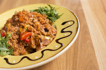 A plate of rice with vegetables. Appetizing healthy rice with vegetables in white plate on a wooden background.
