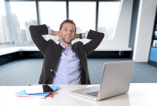attractive businessman happy at office work sitting at computer desk satisfied and smiling relaxed