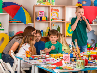 Fototapeta premium Kids playroom organization of children painting and drawing in kid's club. Craft lesson in primary school. They learn to live in a team. Boys at drawing lesson. Kid boy coloring picture in class.