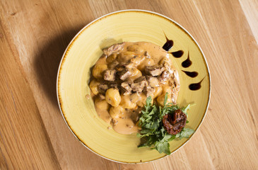 Barbecued beef with roasted potatoes and vegetables. Delicious meat covered with gravy.