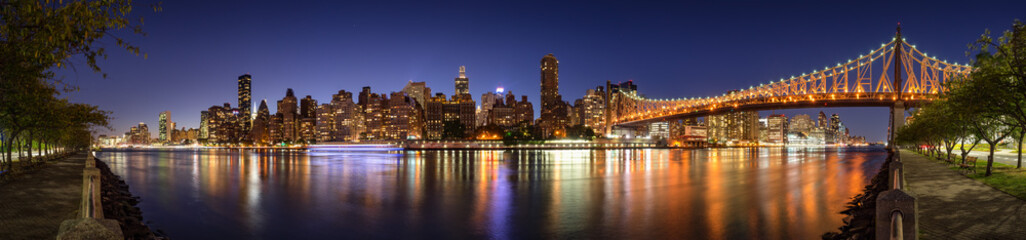 Panoramic evening view of Manhattan Midtown East from Roosevelt Island with the illuminated Ed Koch...