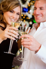 Party: Couple Toasting With Champagne By Christmas Tree