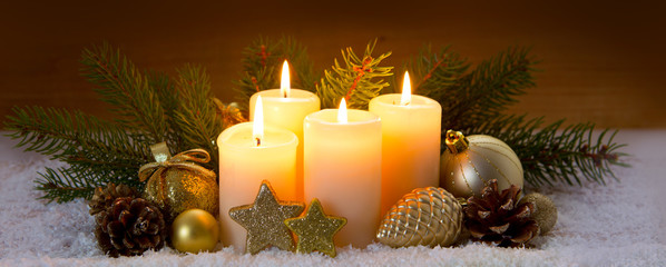 Christmas decoration and four burning Advent candles.