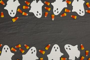 Halloween background with ghosts and candy corn on a slate background
