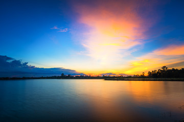 Fototapeta na wymiar Breathtaking sunset landscape with blue sky over lake