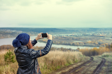 Fototapeta premium girl uses the phone to photograph nature