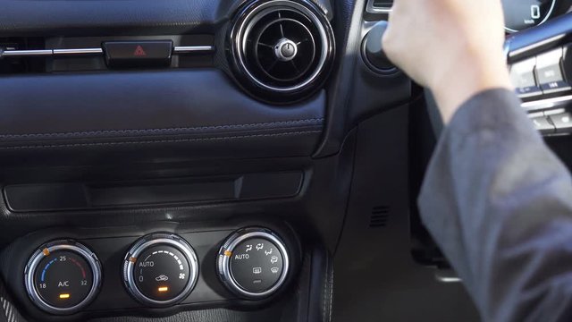 Close up woman's hand, She push start button and turn up or on air condition in modern car.
