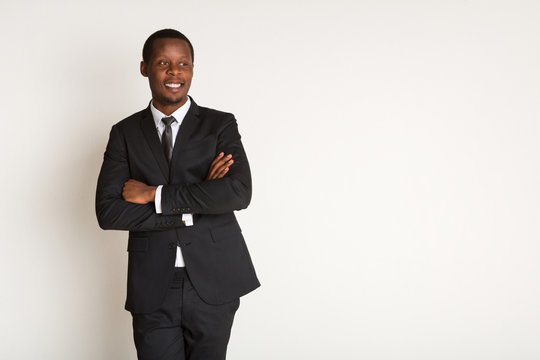 Smiling black male manager in suit stands with arms crossed. Portrait