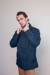 serious young man in an autumn jacket straightens the collar