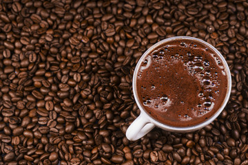    Coffee cup on coffee beans in close up photo.