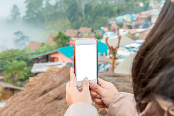 Hand holding cell phone to take a photo view of city on the mountain , blank screen on white