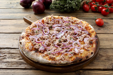 Italienische Pizza mit Thunfisch und Zwiebeln auf rustikalem Hintergrund