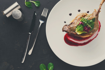 Restaurant meals. Duck confit with vegetables on black backgroun