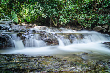 Fototapeta na wymiar A small little waterfall falling on a small lake in Thailand