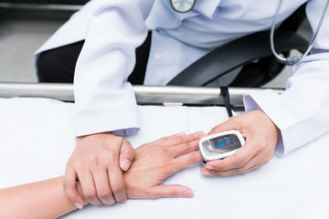 Doctor measuring blood oxygen levels of the sleeping elder patient on bed with oximeter.