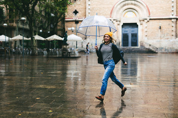 Woman running holding an umbrella on a rainy day.