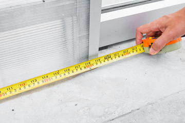 hand holding measurement tape and measuring concrete floor