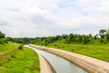 meander concrete water way from dam to city with blue sky among nature