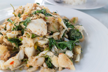 spicy crab stir fry with basil and chili on white dish, closeup shot