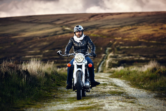 Biker riding vintage motorbike on rural road