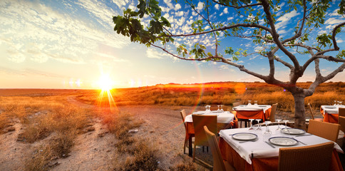 Concepto de gourmet y comer en el restaurante.
Paisaje surrealista de puesta de sol con mesa y...