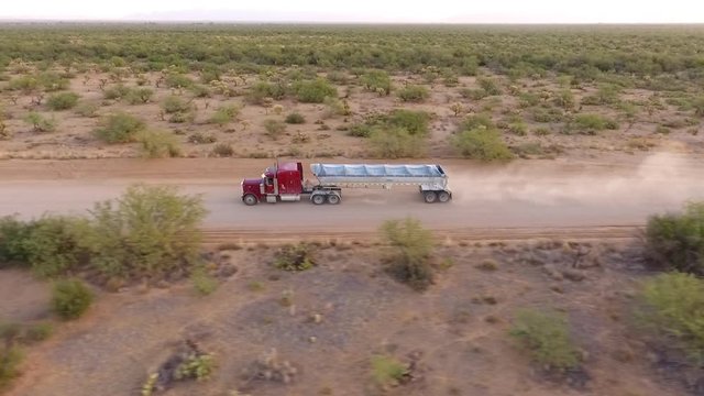 Aerial tracking shot of a tractor trailer on a dirt road
