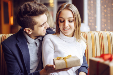 Man and woman in cafe communicate, laughing and enjoying the time spending with each other. Couple in love on a date. A woman receives a gift from a man. Love story.