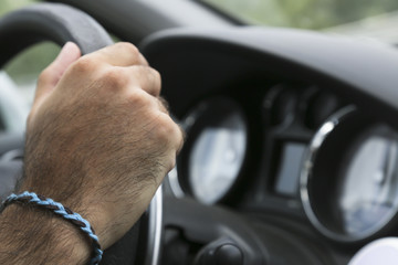 Male driver hands holding steering wheel. 