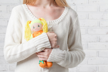 Young woman holding a doll. Leaving childhood