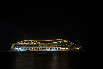 A huge cruise ship at night stands at anchor glowing with very bright lights © Hladchenko Viktor