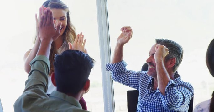 Business executives giving high five in office 