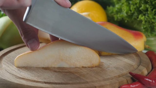 Man's hands cutting the pear into pieces