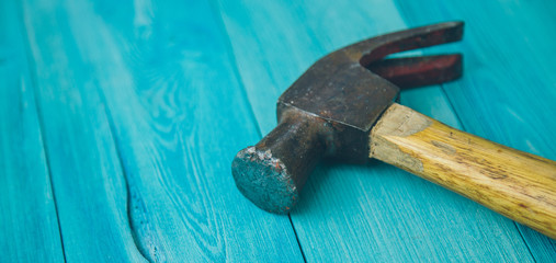 old hammer on a blue wooden background close-up