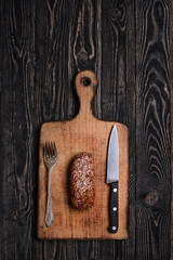 Fork, sausage and knife/Fork, sausage with spices and knife on wooden cutting board.Top view