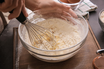 Female chef making dough in glass bowl on kitchen table