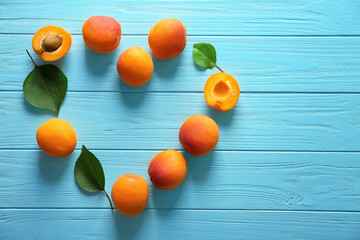 Naklejka na ściany i meble Heart made of fresh apricots on wooden background