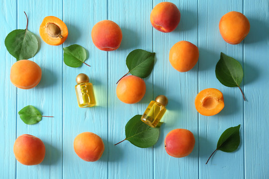 Fresh apricots and bottles with oil on wooden background