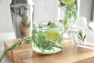 Jar with fresh rosemary drink on wooden board